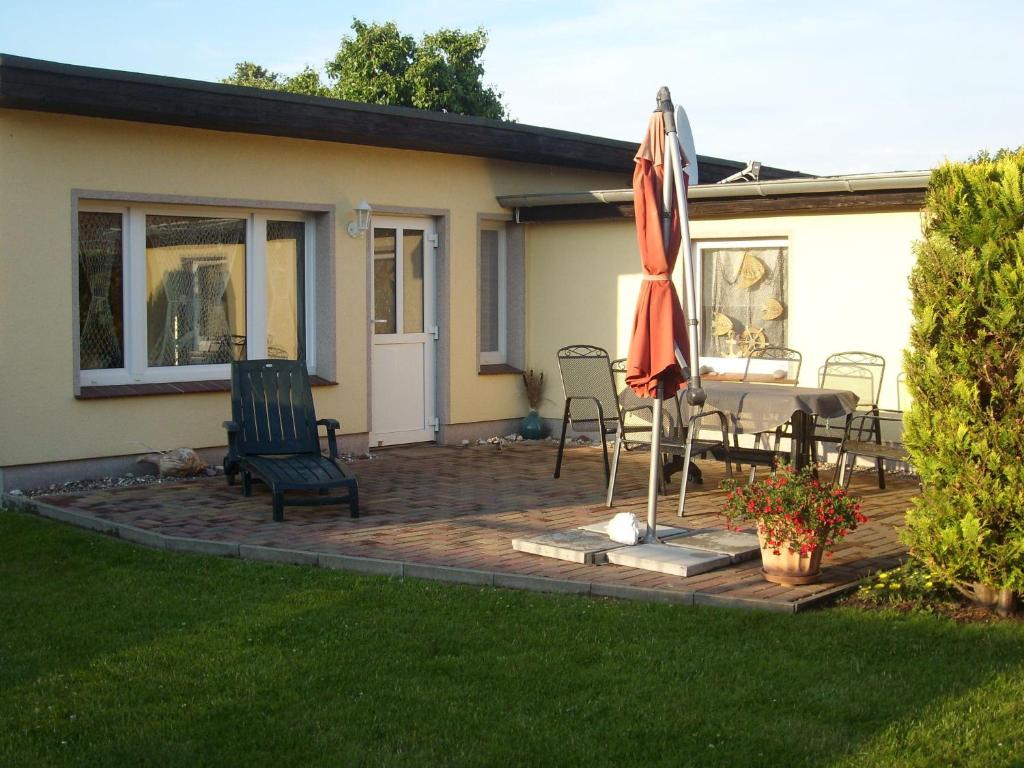 伯尔格伦德-雷特维施Haus-J-Bull-das-Sonneneck-Ferienwohnung-an-der-schoenen-Ostsee-in-Boergerende-Rethwisch的庭院配有遮阳伞和桌椅。