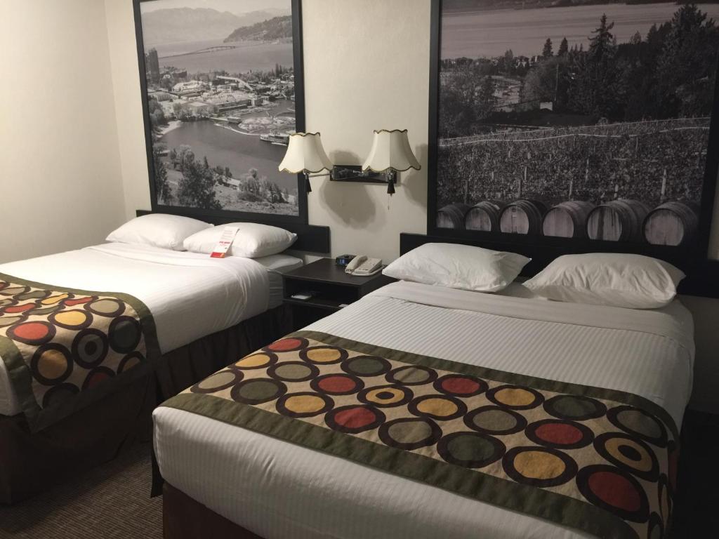 基洛纳基隆拿速8酒店的两张位于酒店客房的床,墙上挂有照片