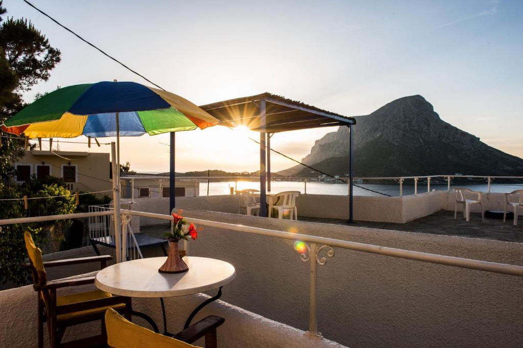 马苏里Hotel Aegean Home Studios & Apartments的阳台配有桌子和雨伞。