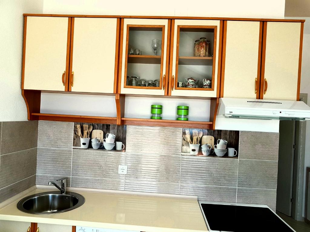 蒂瓦特Apartman Milovic的厨房配有水槽和带杯子的橱柜