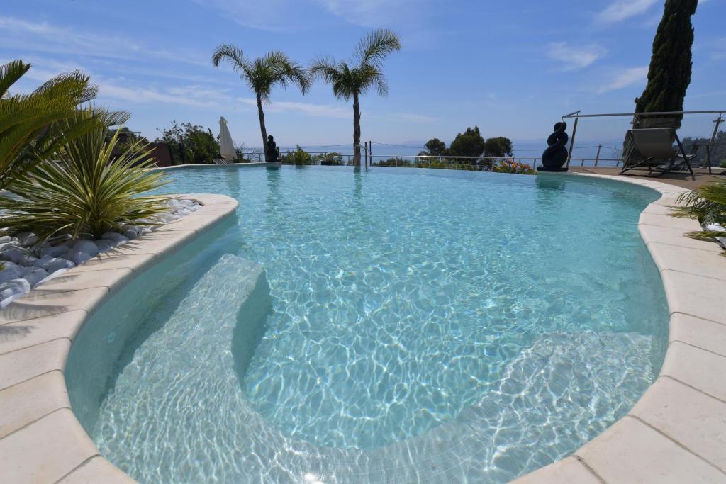 勒·雷约尔·卡纳德尔·苏尔Les Lauriers Roses的一座拥有蓝色海水和棕榈树的游泳池