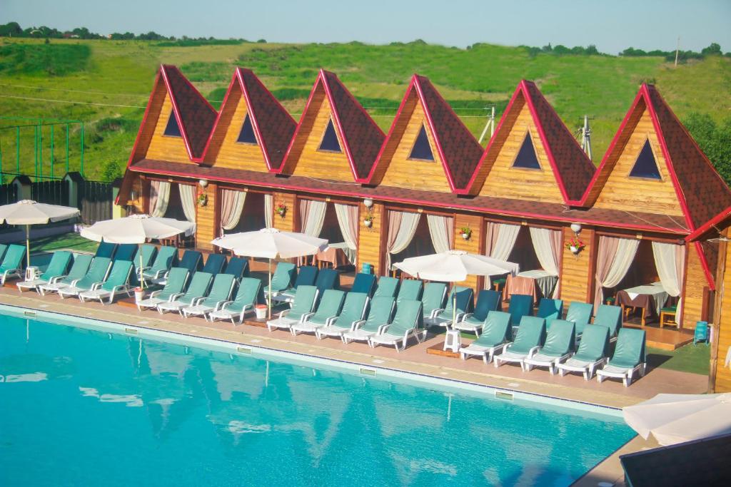 KhmelëvaUsadba Berezino的酒店前方的游泳池配有椅子和遮阳伞