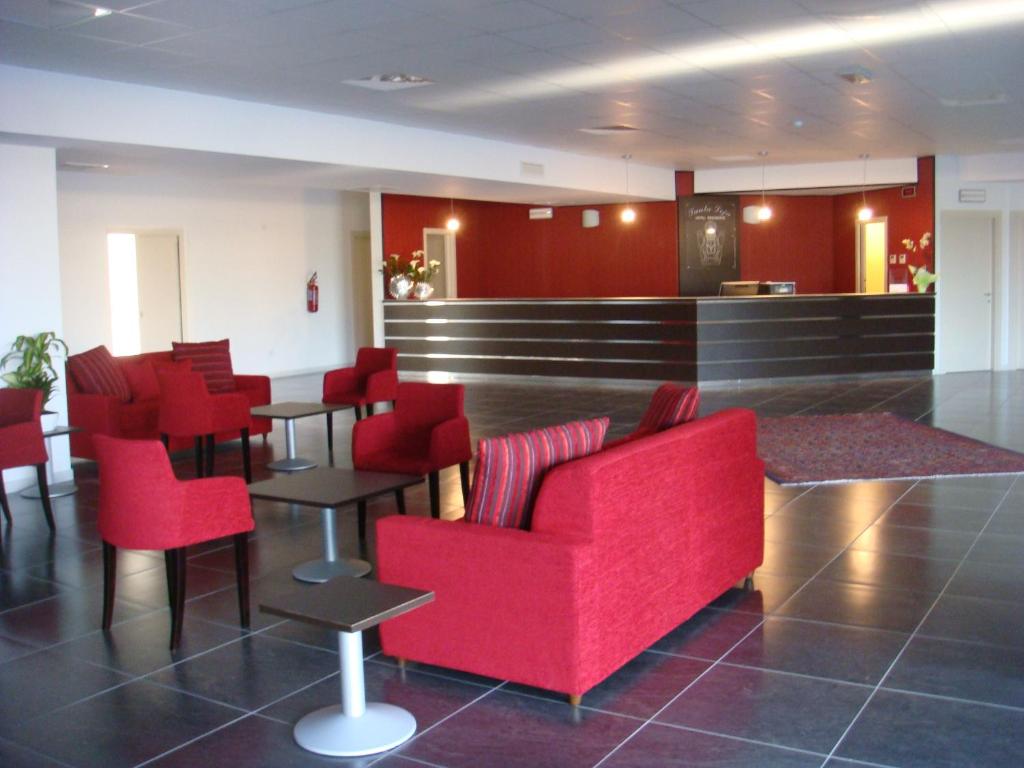 TitoSanta Loja Hotel Residence的一间设有红色椅子的等候室和一间酒吧