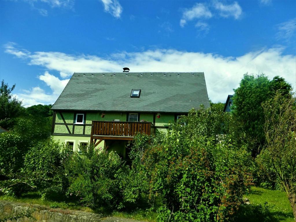 卡劳特格瑞斯赫Michel's Ferienwohnung的绿色房子,设有门廊和甲板