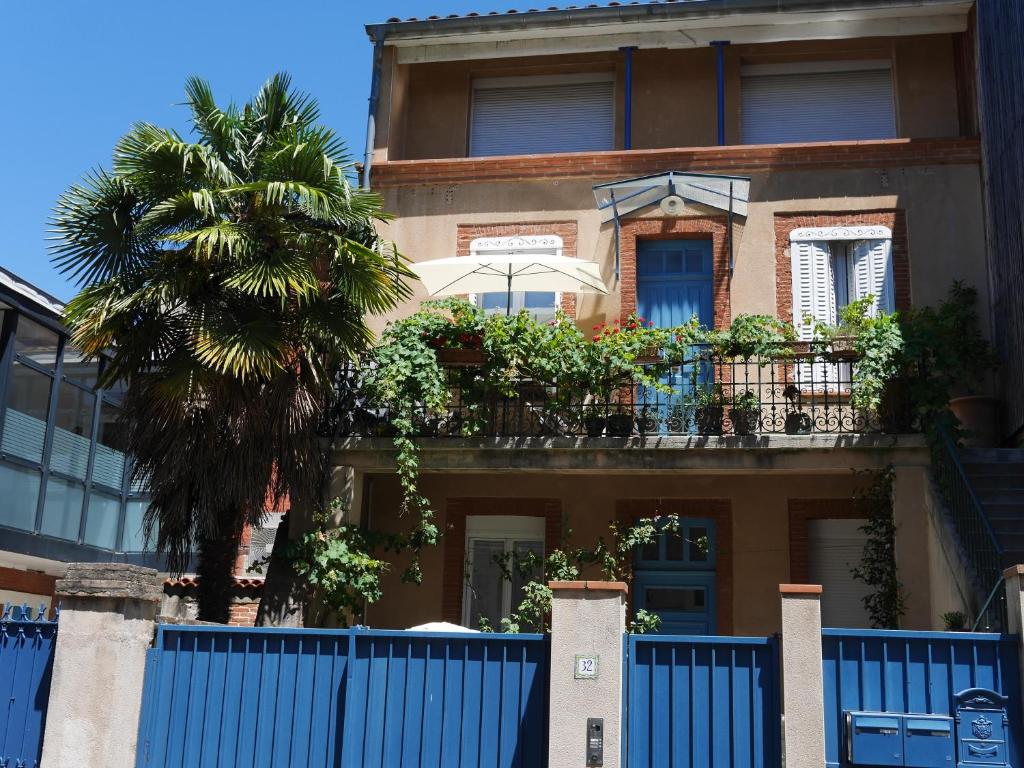 图卢兹Les Loges des Chalets的一座拥有蓝色栅栏和棕榈树的建筑