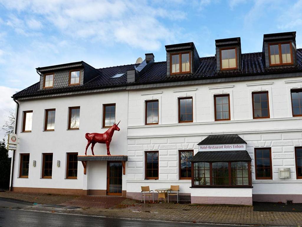 都伦-埃菲尔Hotel-Restaurant Rotes Einhorn Düren *** Superior的一座白色的大建筑,上面有马雕像
