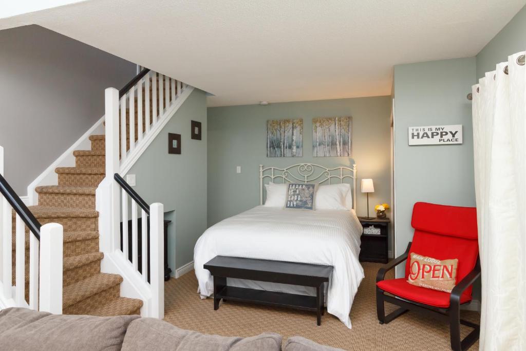 蓝山蓝山山畔复式公寓的一间卧室设有一张床,楼梯设有红色椅子