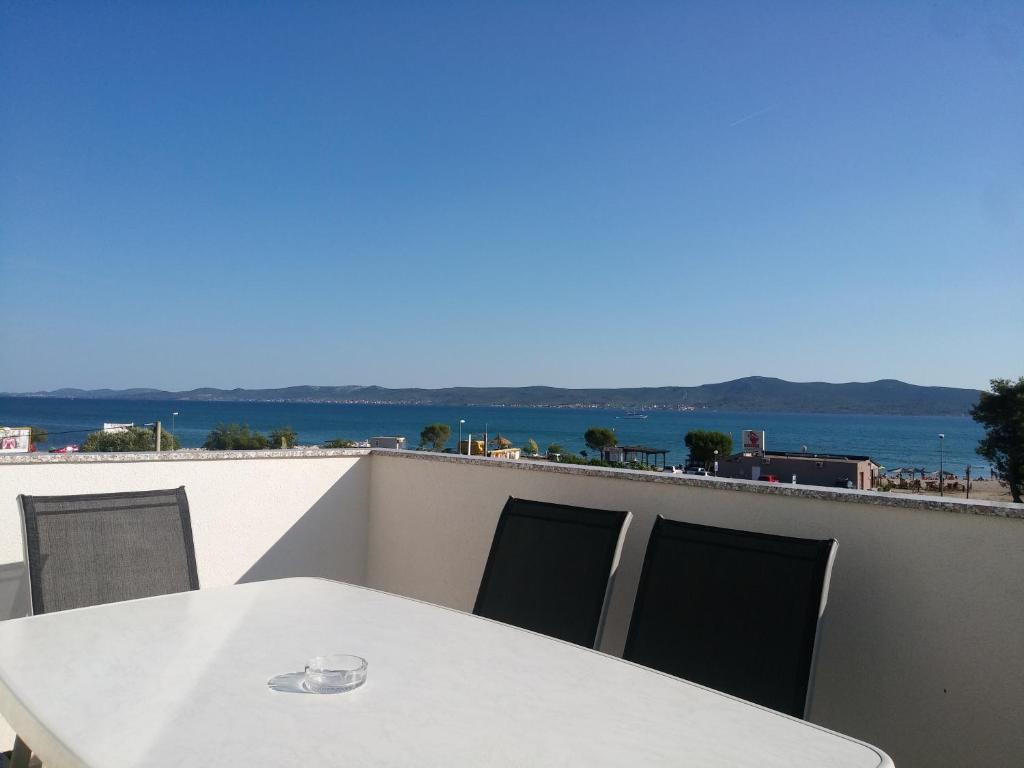 苏科尚Solmaris apartments的阳台上配有白色的桌椅,享有海景
