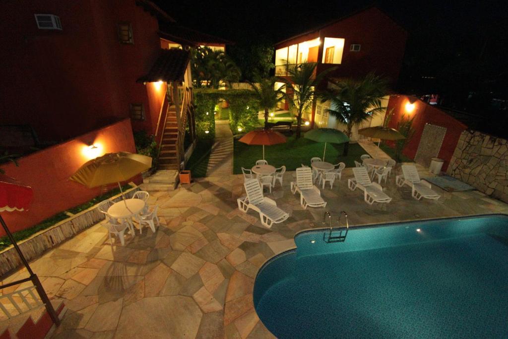 皮雷诺波利斯Pousada Recanto的后院设有游泳池、椅子和遮阳伞