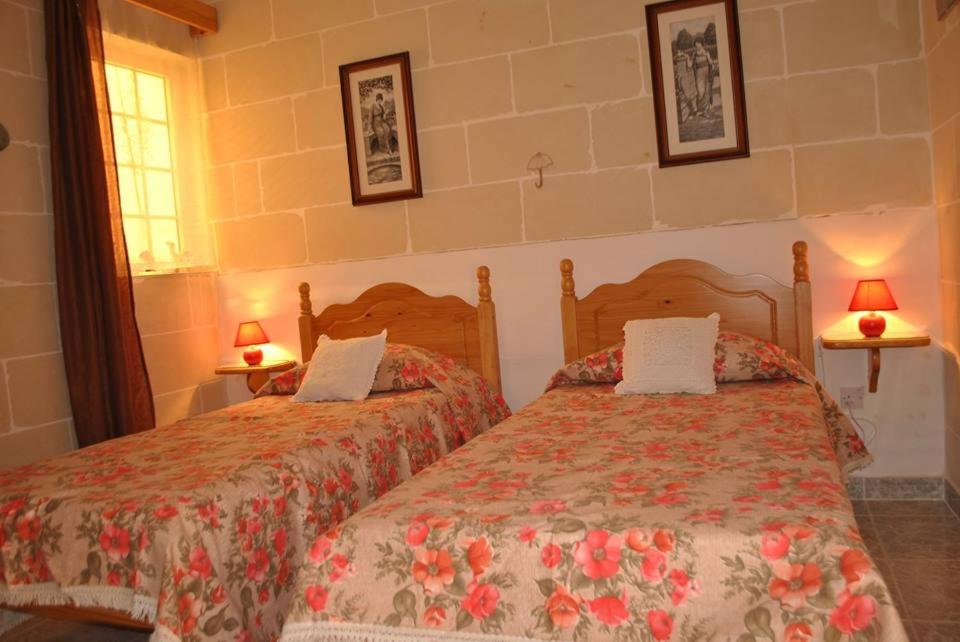 MunxarSt Nicholas Crt的卧室内的两张床,墙上有两盏灯