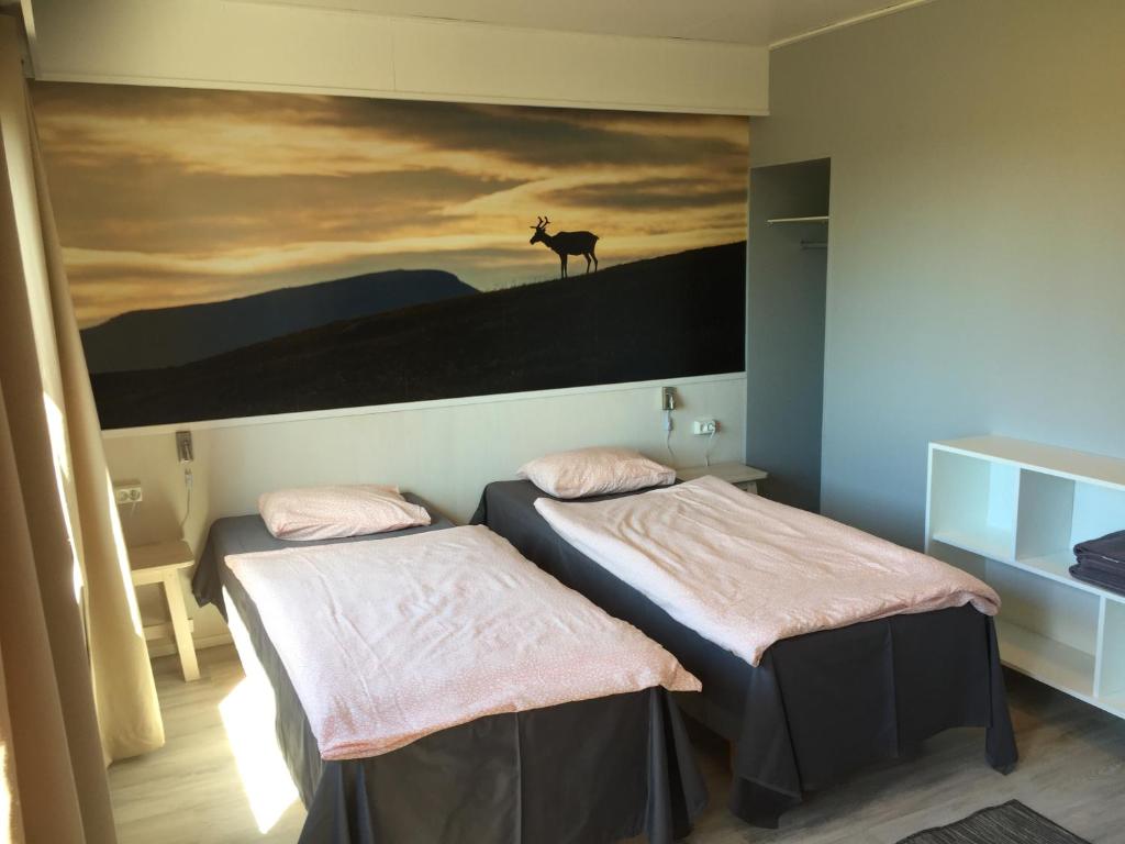 罗瓦涅米博瑞李斯宾馆的墙上挂着鹿画的房间的两张床