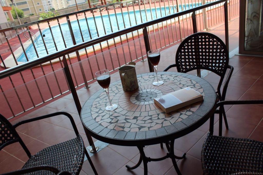 奥罗佩萨德尔马Residencial Algaida的阳台上的桌子和两杯葡萄酒