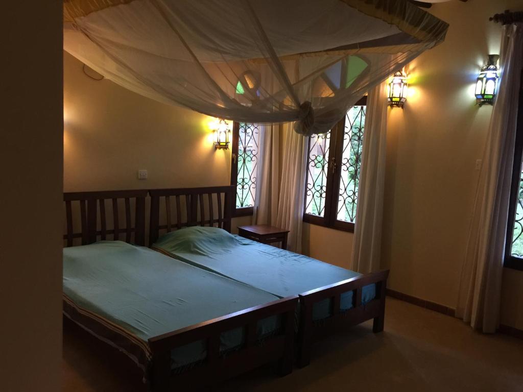迪亚尼海滩马鲁拉公园度假屋的一间卧室设有一张天蓬床和两个窗户