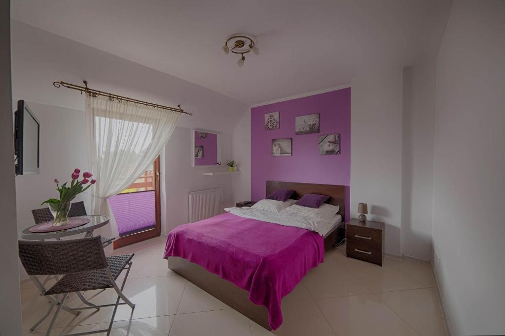 雅罗斯瓦维茨4 strony świata的一间卧室配有一张紫色的床和一张桌子及椅子