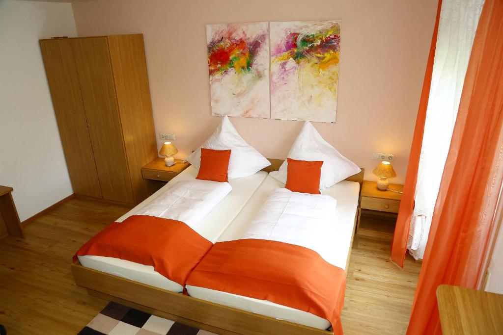 申瓦尔德Landhotel Garni Schweizerhaus的一间卧室配有带橙色和白色枕头的床