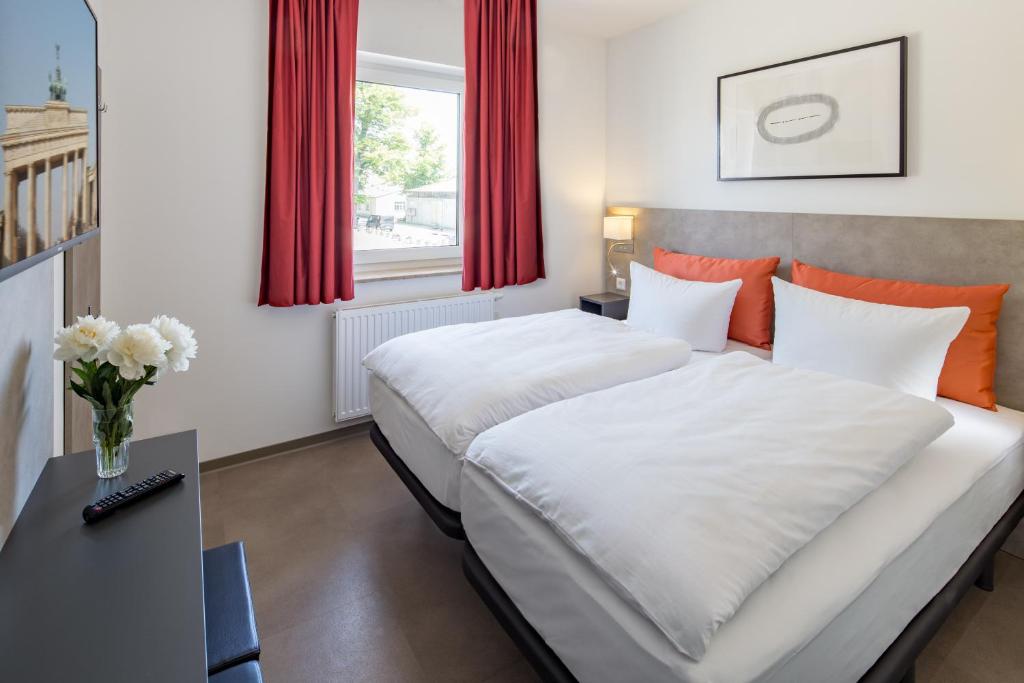 柏林TRIO Apartment Hotel Berlin的一间卧室设有两张床和一张花瓶桌子。