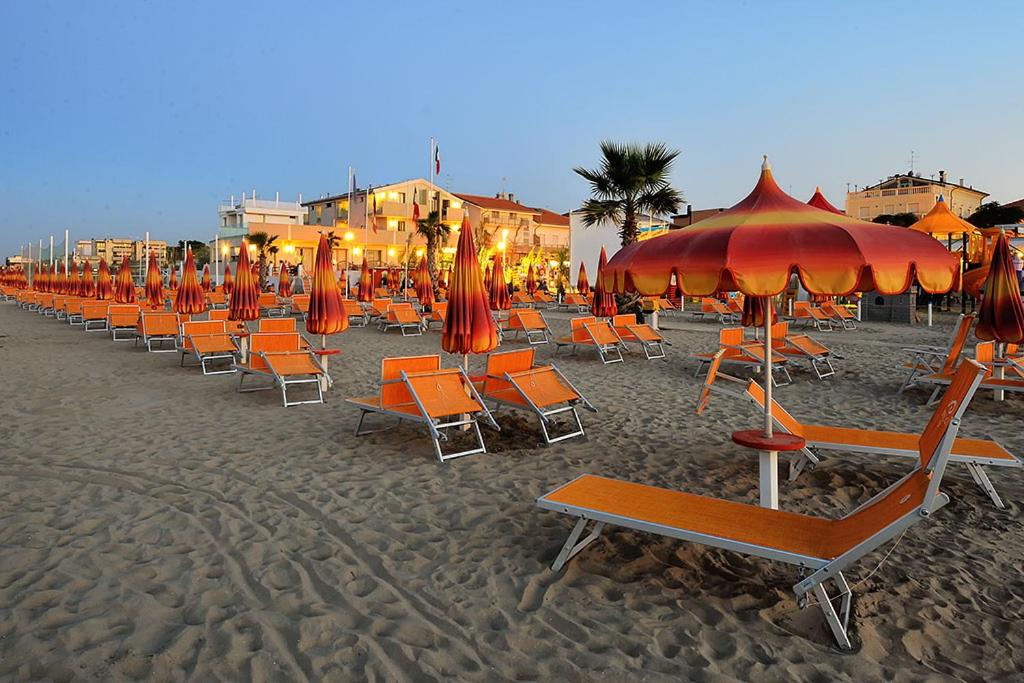 里米尼卡瓦露西奥圣马力诺住宅酒店的海滩上的一排椅子和遮阳伞