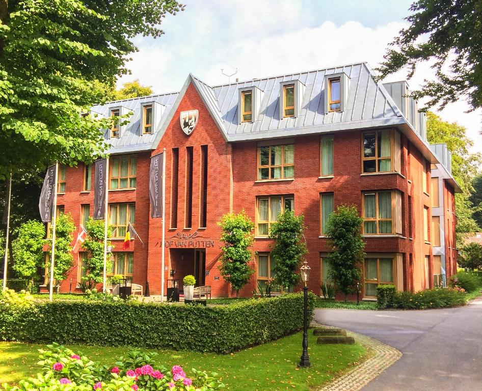 皮滕霍夫万普滕酒店的一座种满树木和鲜花的大型红砖建筑