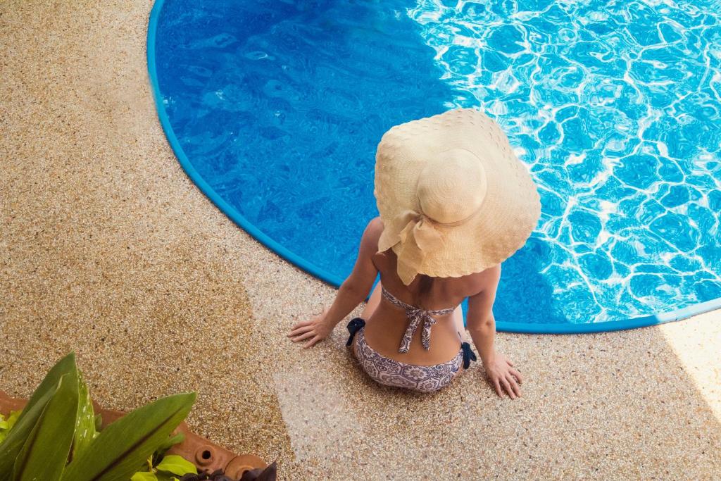 奥南海滩西埃斯塔别墅的坐在游泳池的戴帽子的女人
