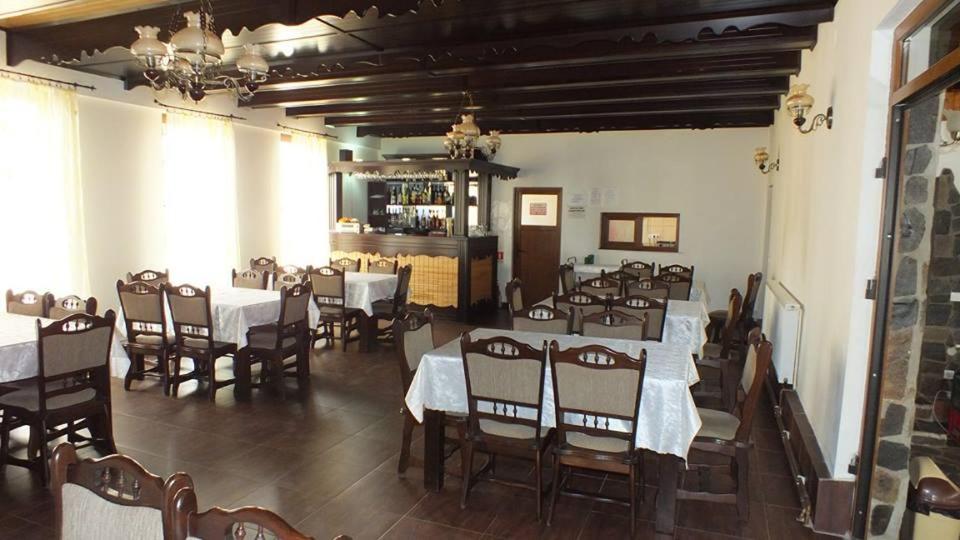 瑟彭察Pensiune Restaurant la Pogace的一间带桌椅的用餐室和一间酒吧