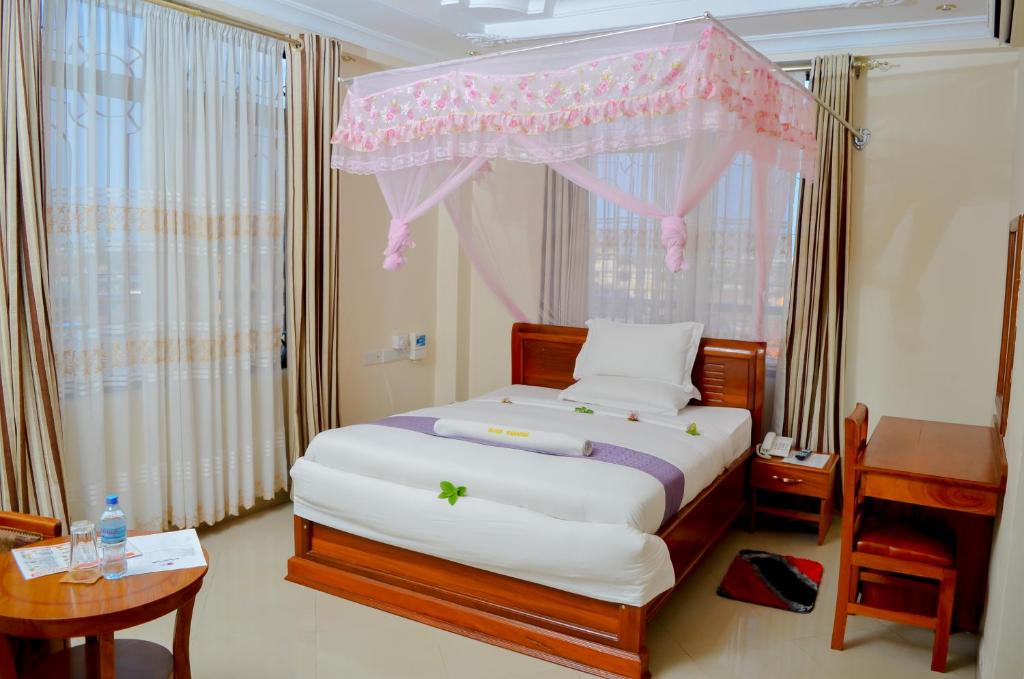 达累斯萨拉姆银色天堂酒店的一间卧室配有一张粉红色天蓬床