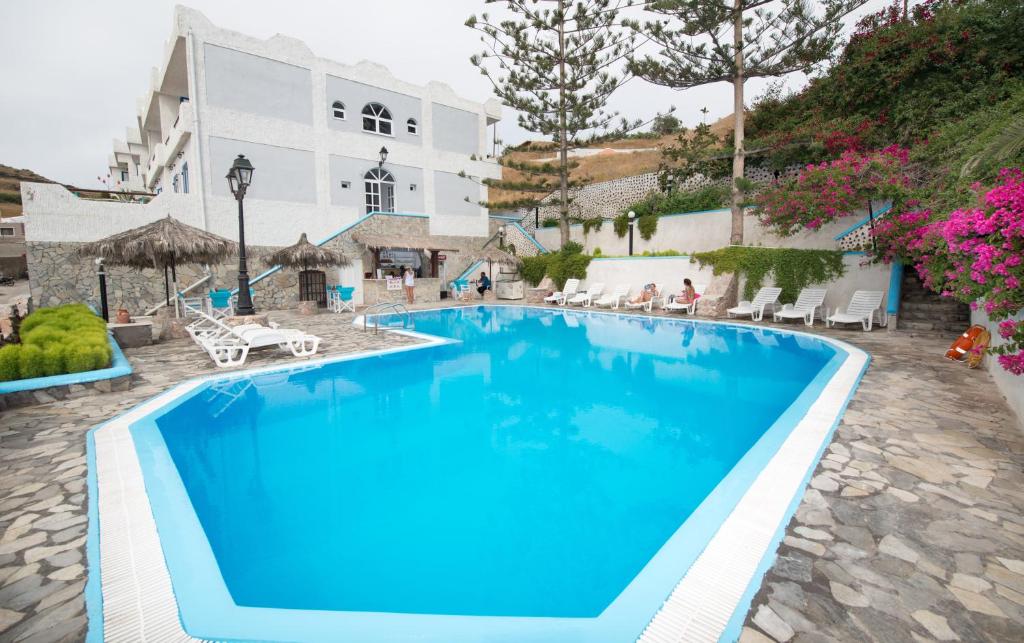 费拉珀特卡斯特洛酒店的白色建筑前方的大型蓝色游泳池