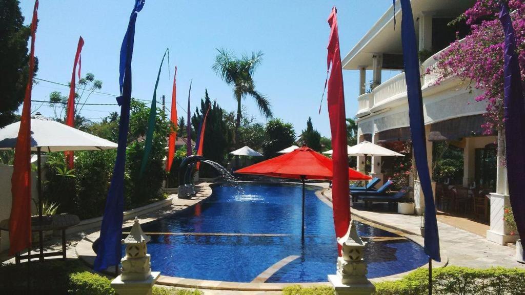罗威那巴厘岛天堂精品度假酒店 的一个带红色遮阳伞和喷泉的游泳池