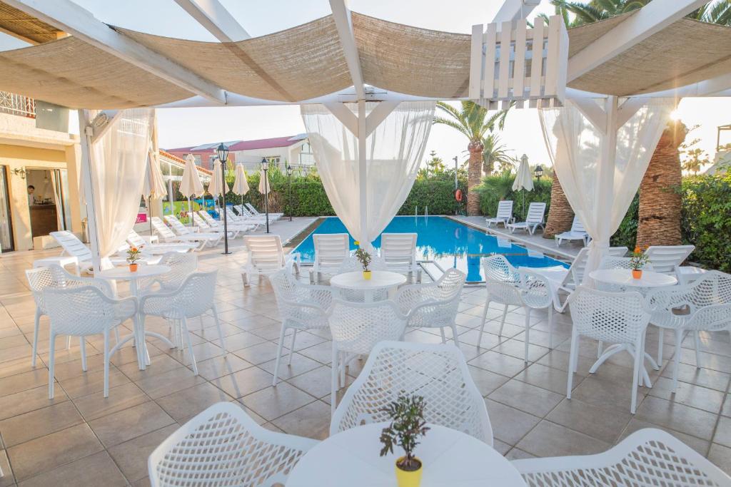 普拉坦斯Creta Aquamarine Hotel的一个带白色桌椅的庭院和一个游泳池