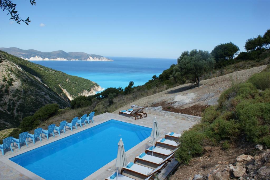 AnomeriáMyrtos View Apartments的一个带椅子的游泳池,背景是大海