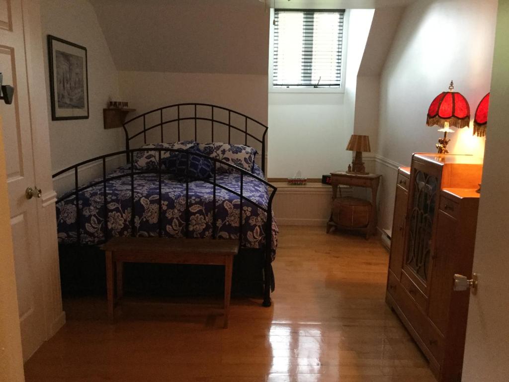 维多利亚维尔La Maison des Éboulis的一间卧室配有一张床,铺有木地板