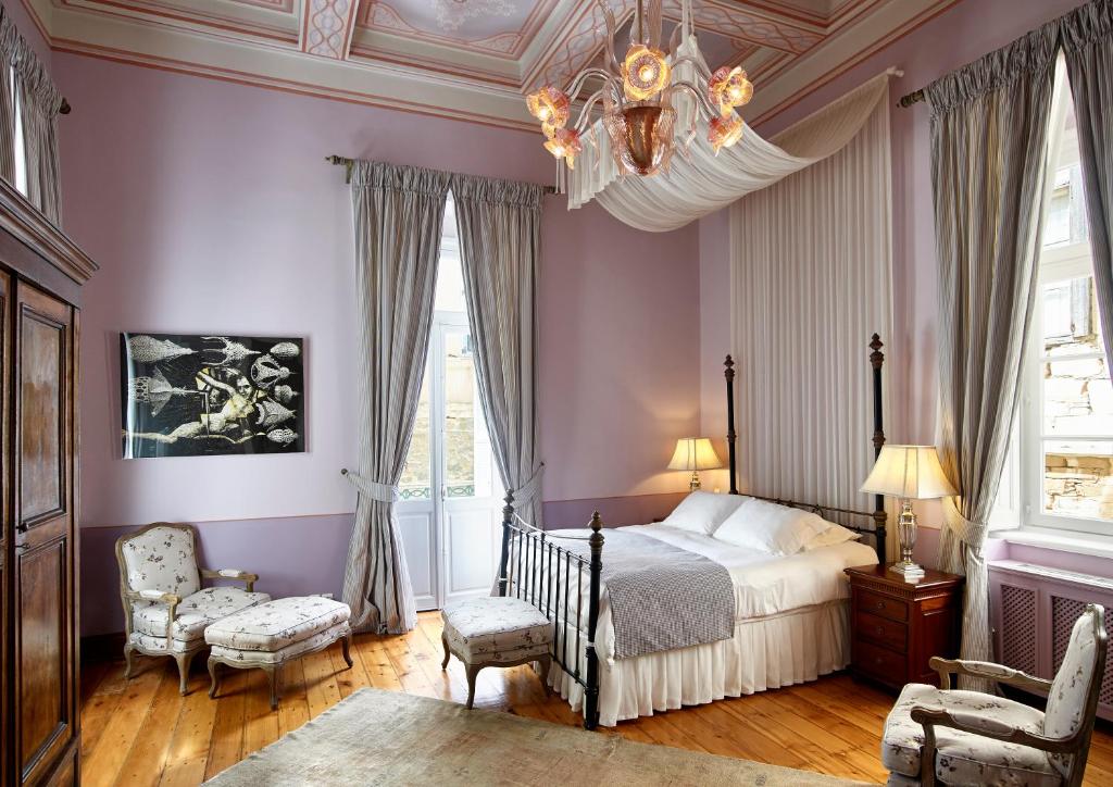 埃尔莫波利斯普鲁斯酒店的一间卧室设有紫色的墙壁、一张床和一个吊灯。