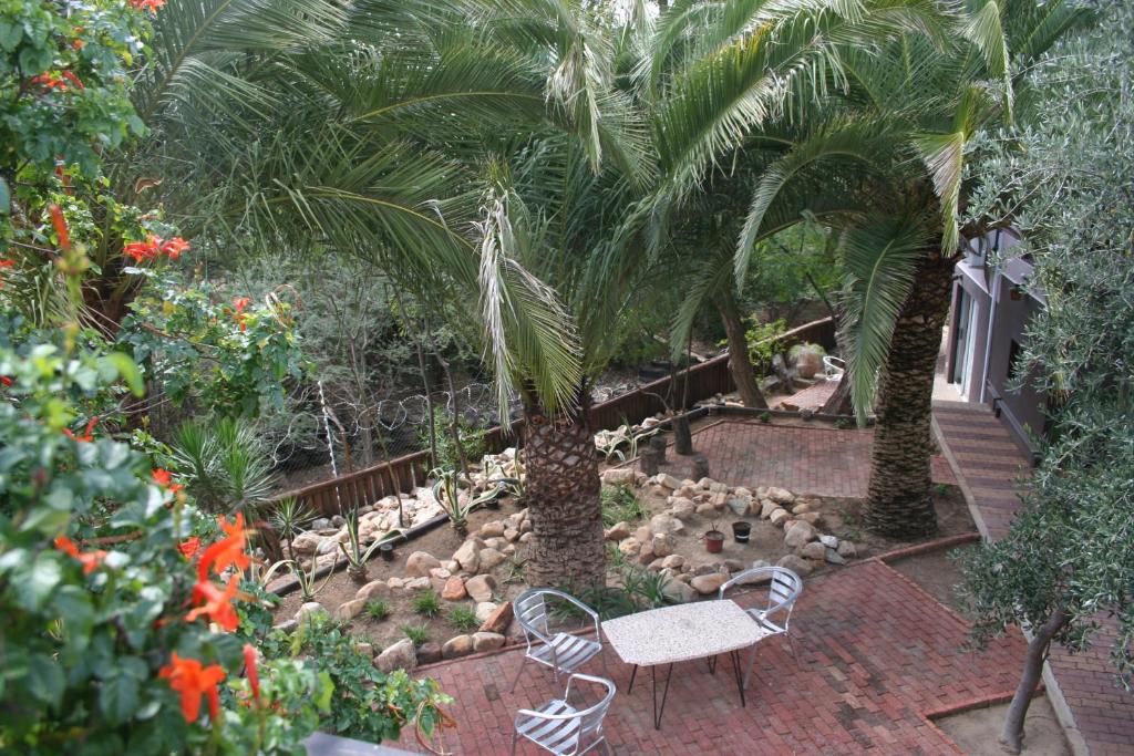 温特和克De Vagebond Hotel-Pension的种有长凳、棕榈树和鲜花的花园