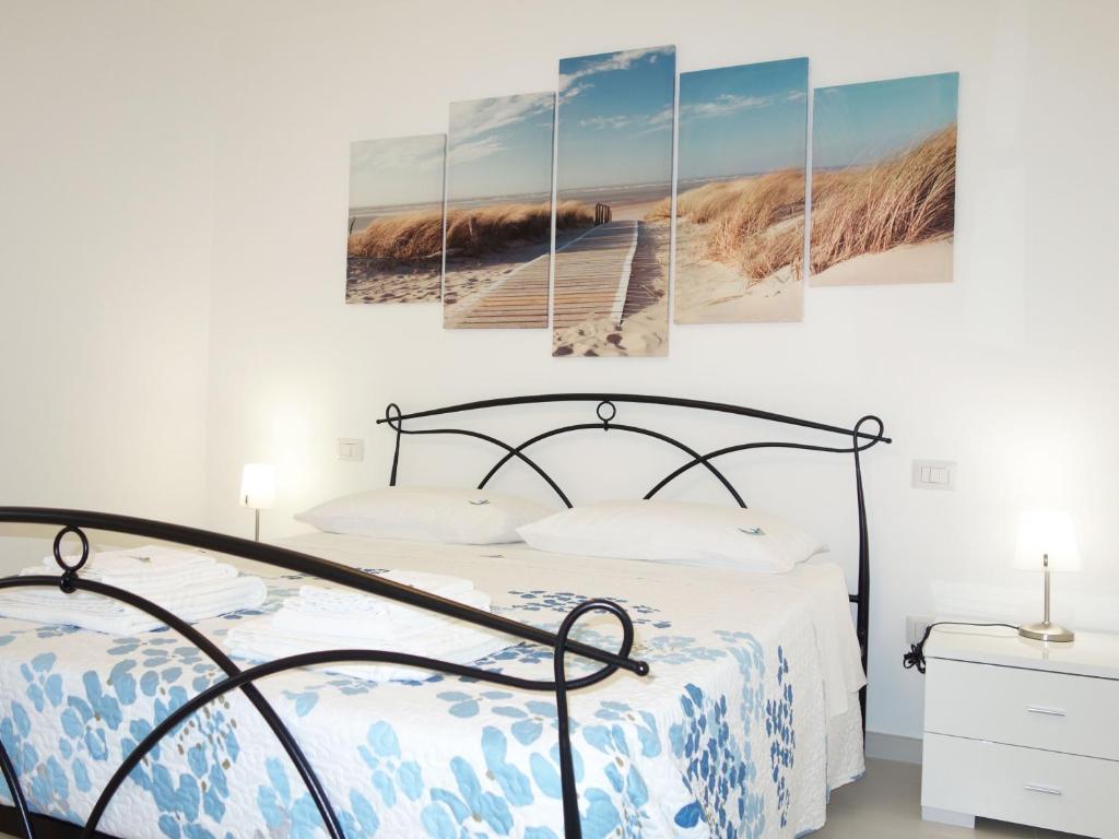 托雷拉皮罗La Baia Apartments的一间卧室,配有一张床,海滩上设有木板路