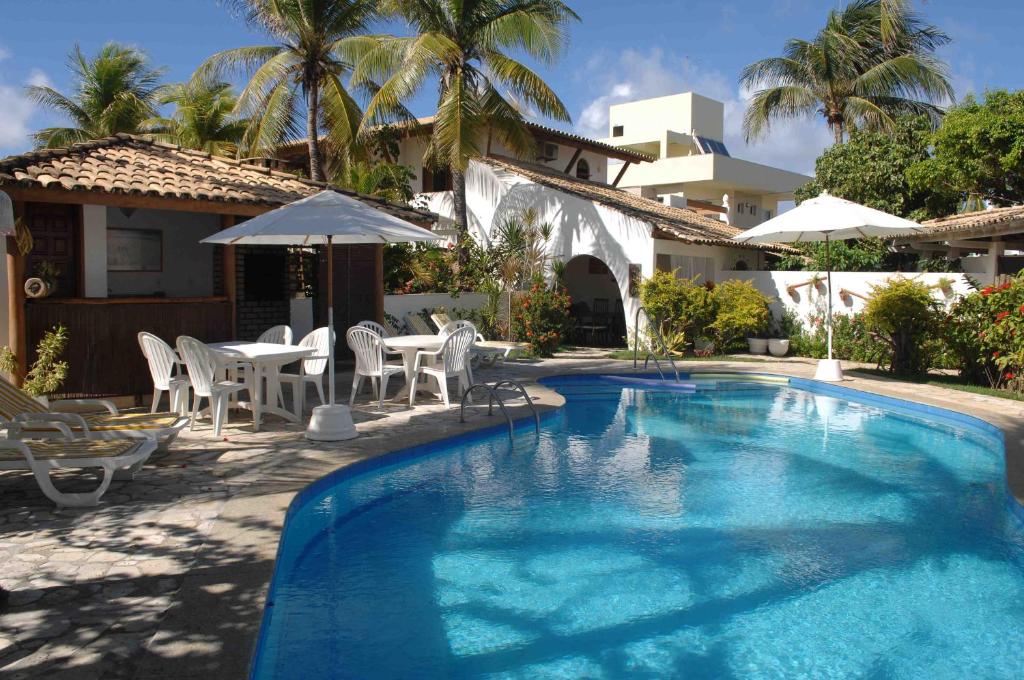 瓜拉久巴Casa das Ondas Guarajuba的房屋旁的游泳池配有椅子和遮阳伞
