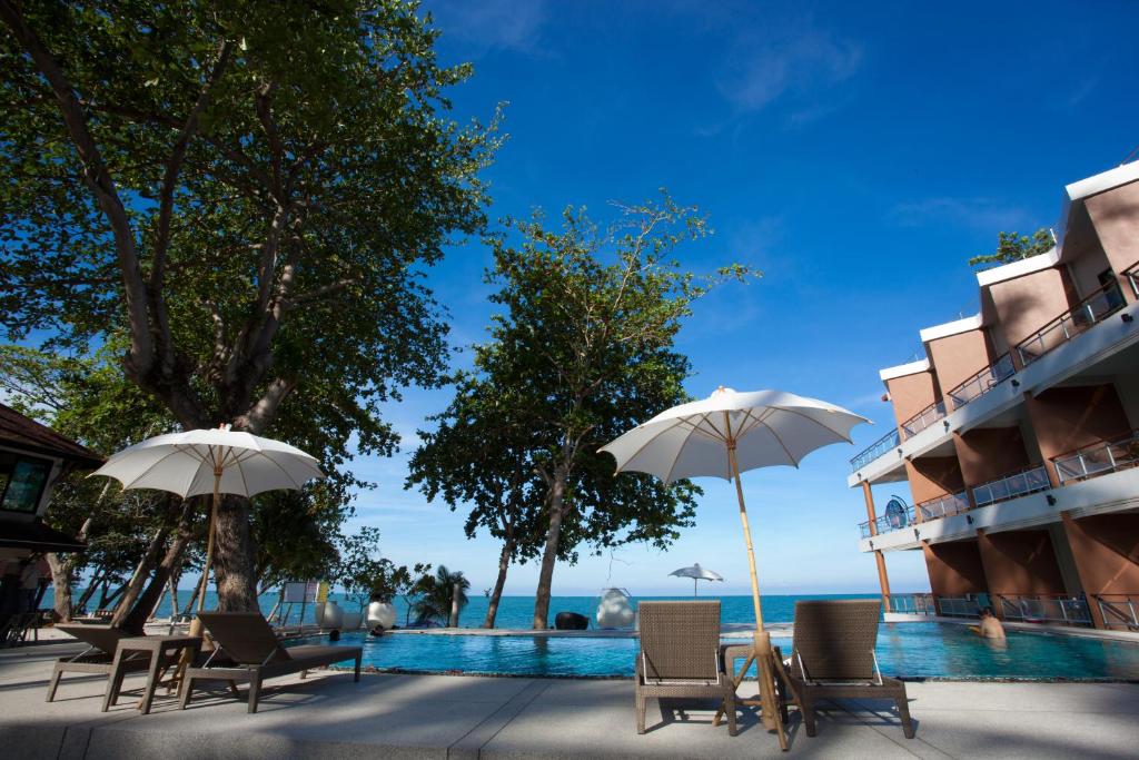 锡春普拉萨恩索克别墅海滩度假村的一组椅子和遮阳伞,位于游泳池旁