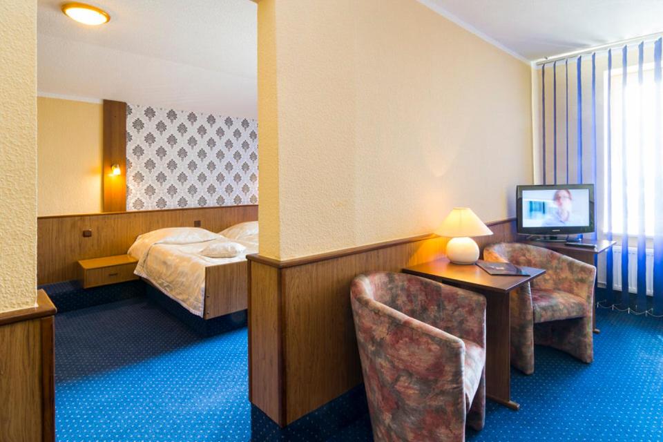 什切青维多利亚酒店的酒店客房,配有一张床、一张桌子和椅子
