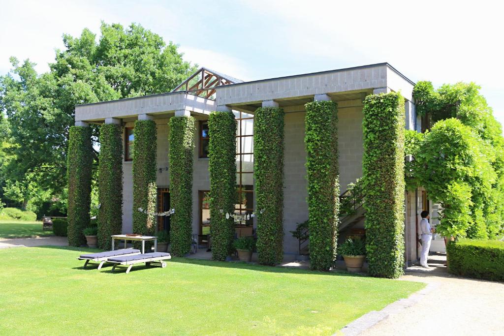 拉于尔普源头花园住宿加早餐旅馆的常春藤覆盖的楼房,在院子里设有长凳