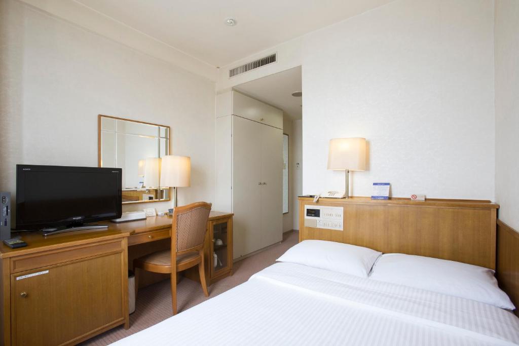 千叶特托然泽幕张稻毛海岸酒店的酒店客房配有一张床和一张书桌及一台电视