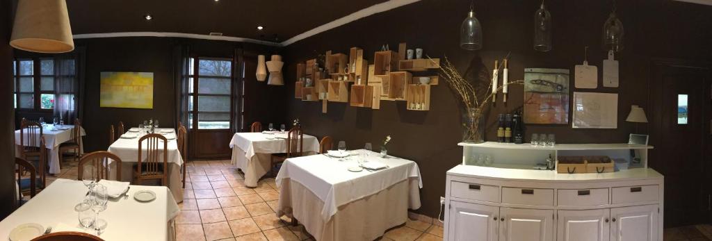 奥拉贝里亚泽兹里奥尼亚旅馆的餐厅设有白色的桌椅和吊灯。