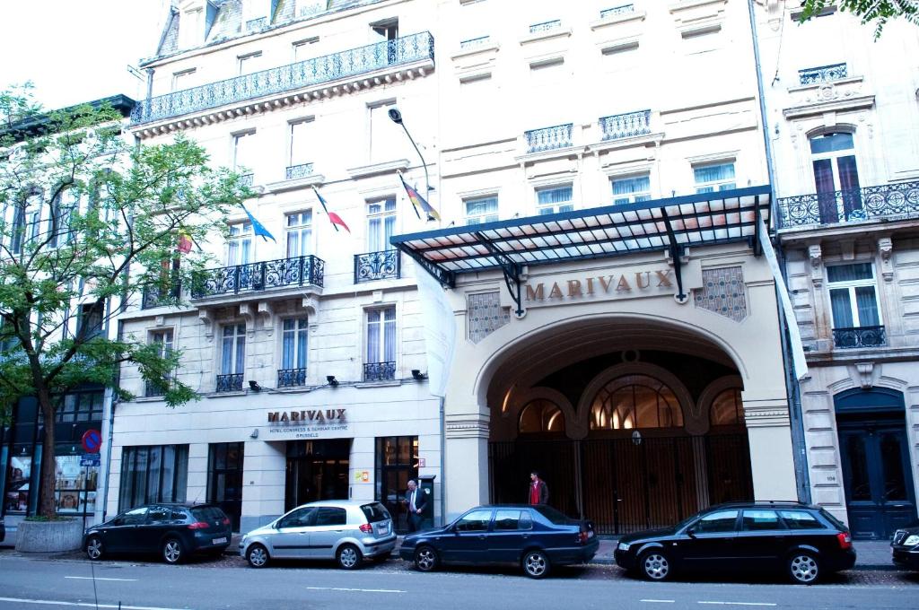 布鲁塞尔马里伏酒店的一座白色的大建筑,前面有汽车停放