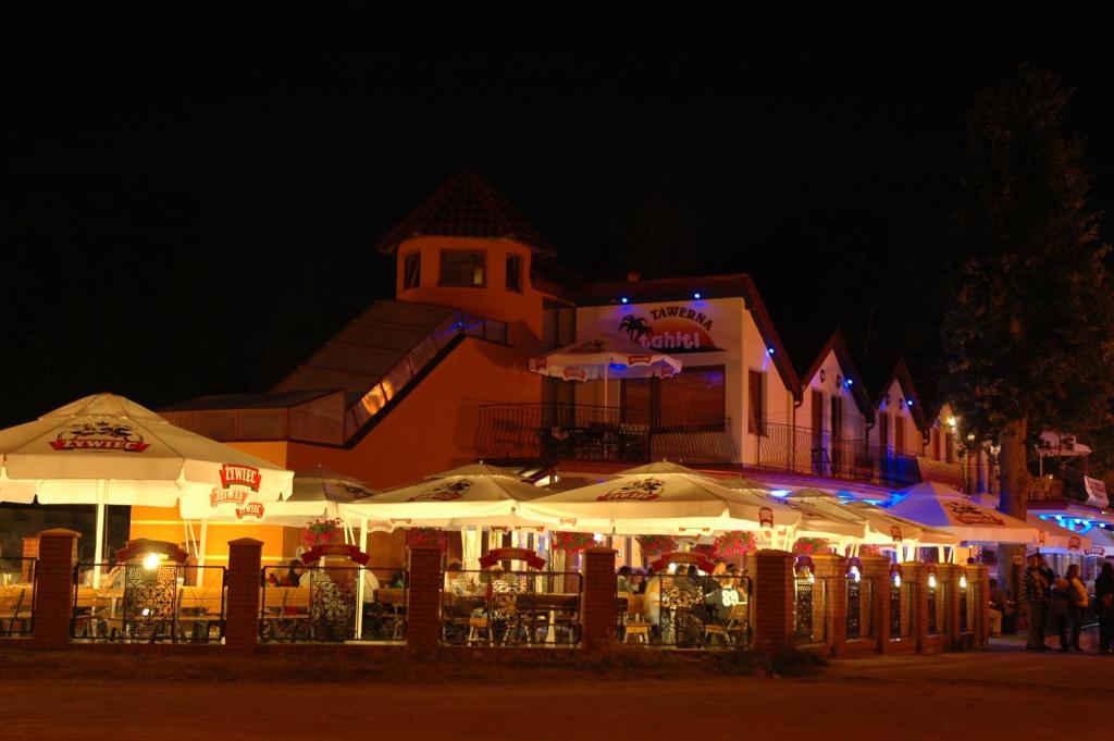 罗威Pensjonat Tahiti的一座晚上带桌子和遮阳伞的建筑
