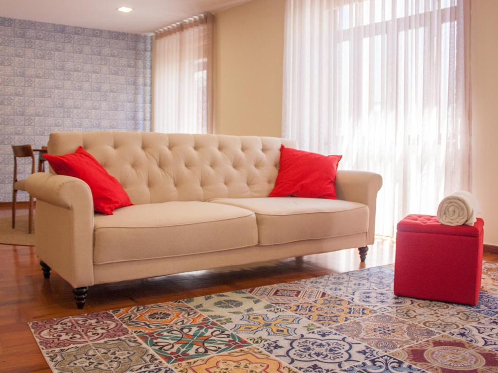 波瓦-迪瓦尔津Varzim Guesthouse的客厅里一张带两个红色枕头的沙发