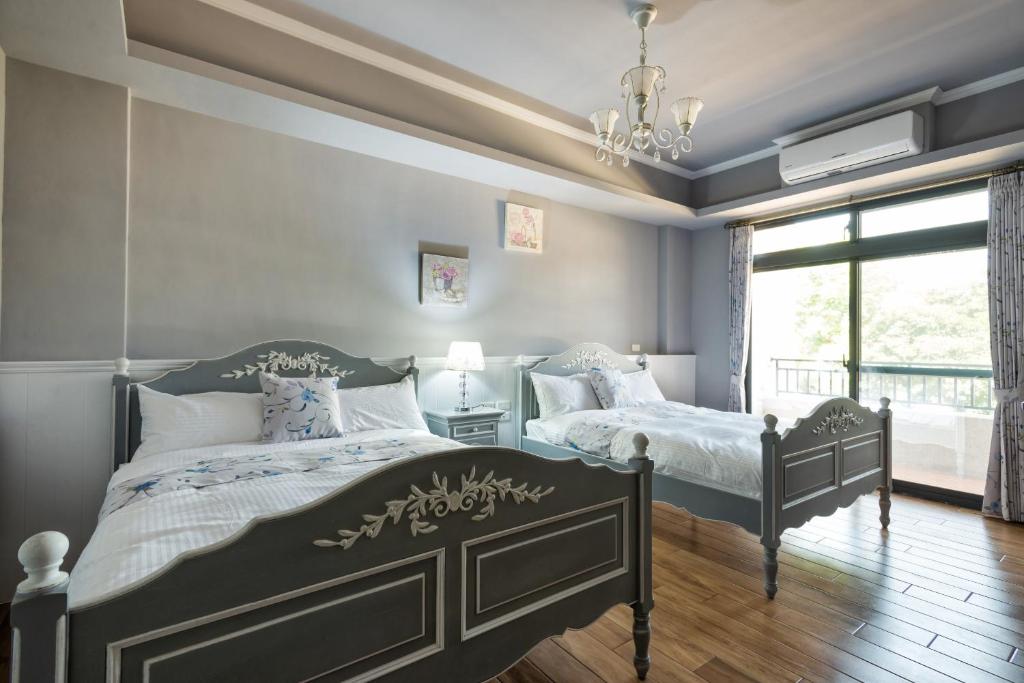 花莲市鸢尾花渡假民宿的一间卧室设有两张床、一个窗户和一个吊灯。