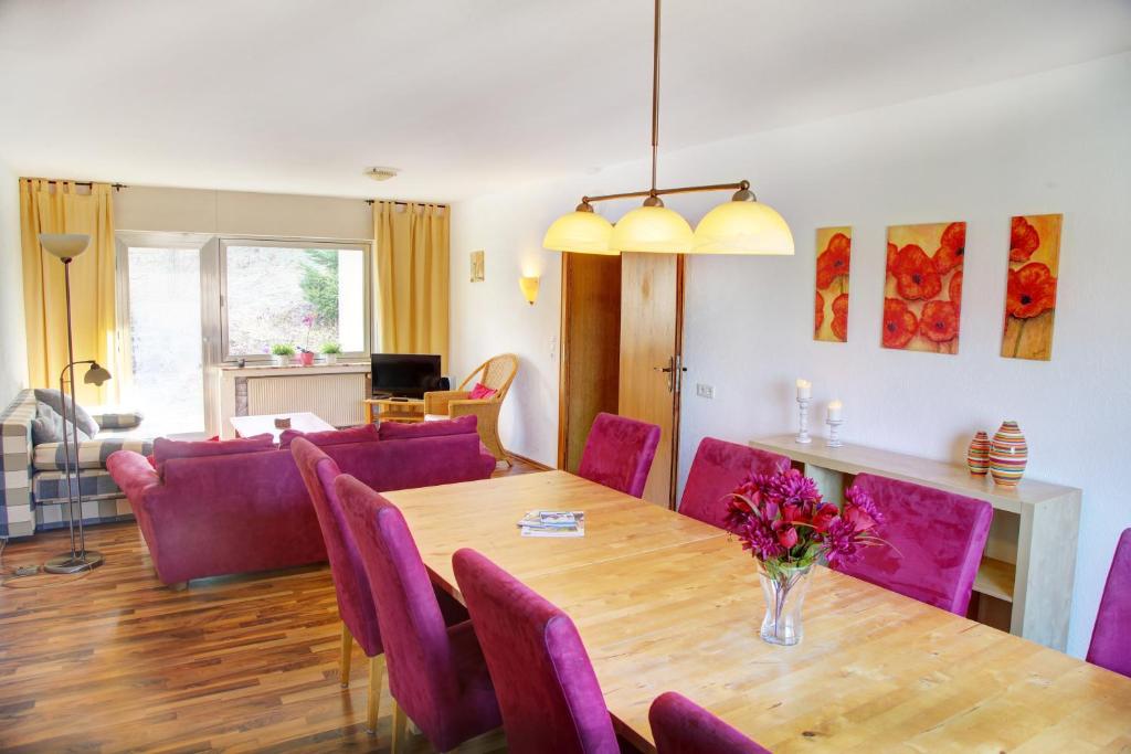 哈伦贝格Haus Nova am Bollerberg的一间带桌子和紫色椅子的用餐室