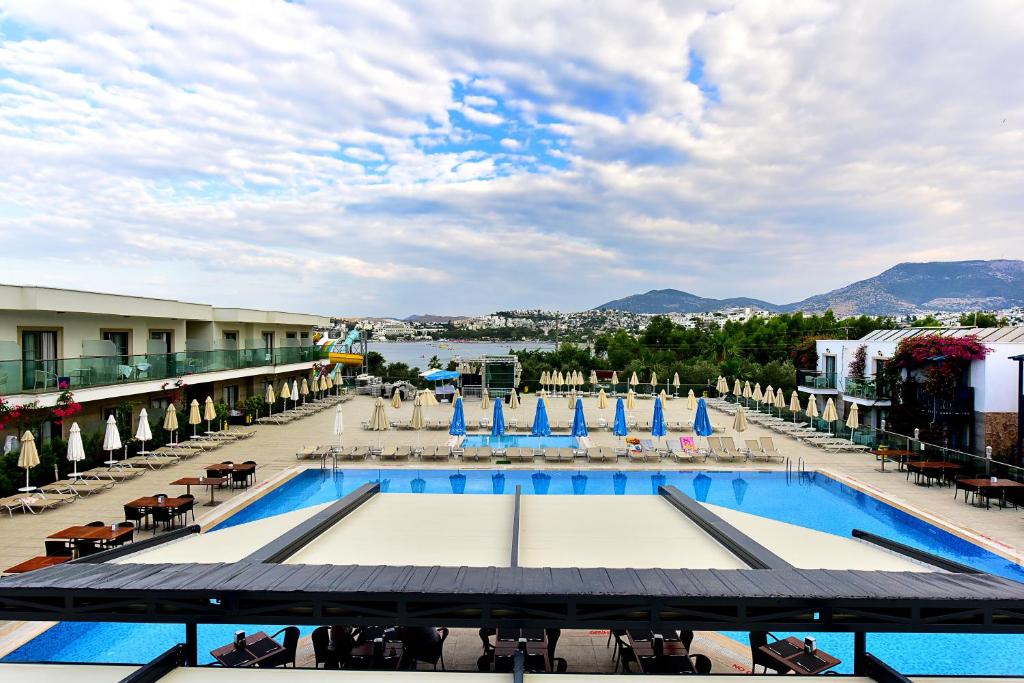 居姆贝特茉莉海滩酒店的享有带椅子和遮阳伞的度假村游泳池的景致