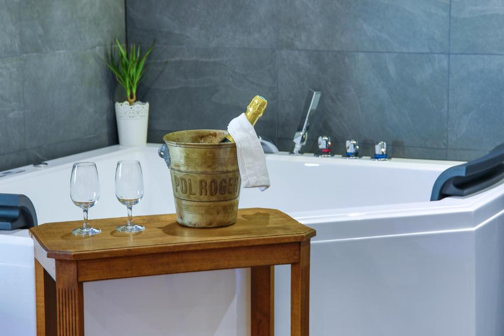 科尔马Suites Residences Spa的带浴缸和桌子上两杯酒杯的浴室