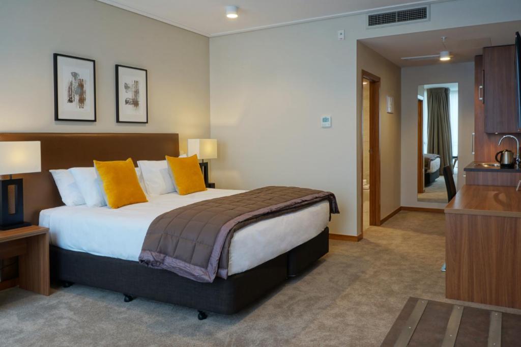 但尼丁达尼丁维多利亚酒店的一间卧室配有一张带黄色枕头的大床