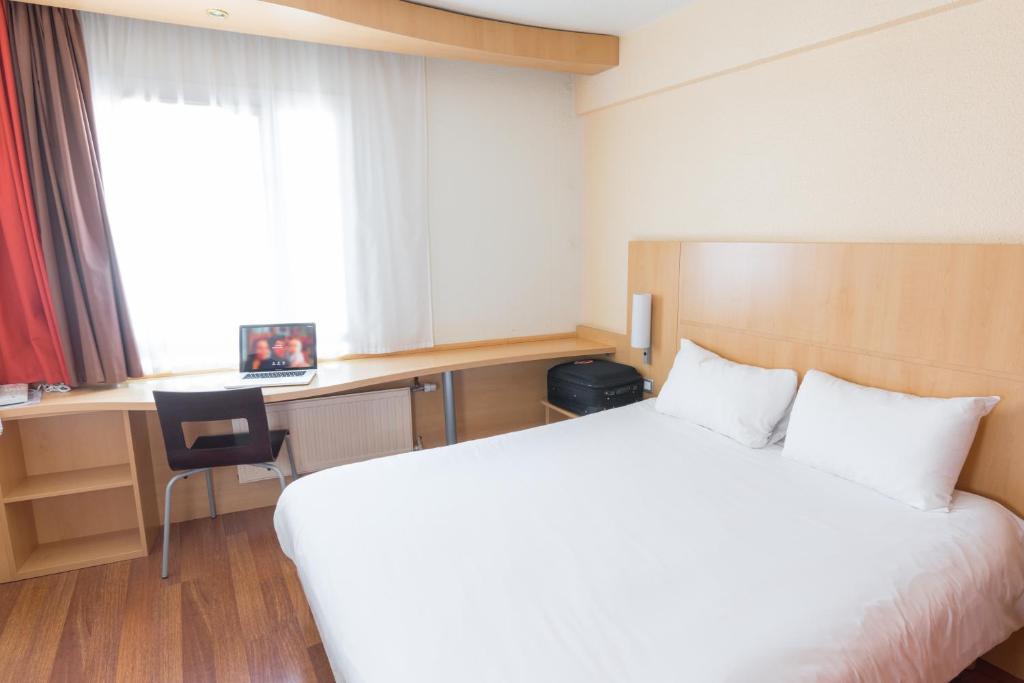 敦刻尔克敦刻尔克宜必思酒店的配有一张床、一张书桌和一扇窗户的酒店客房