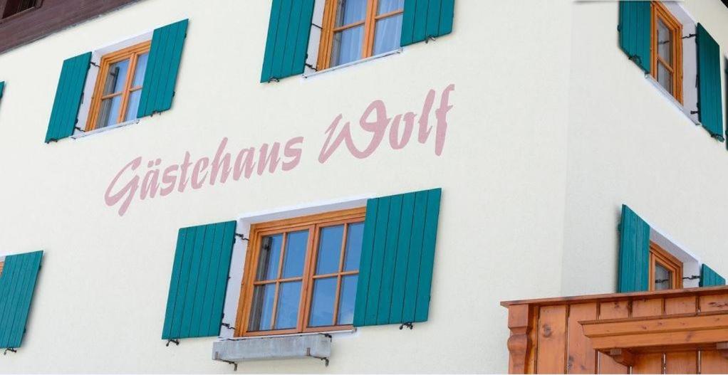 巴赫Gastehaus Wolf的白色的建筑,有绿色的窗户和标志