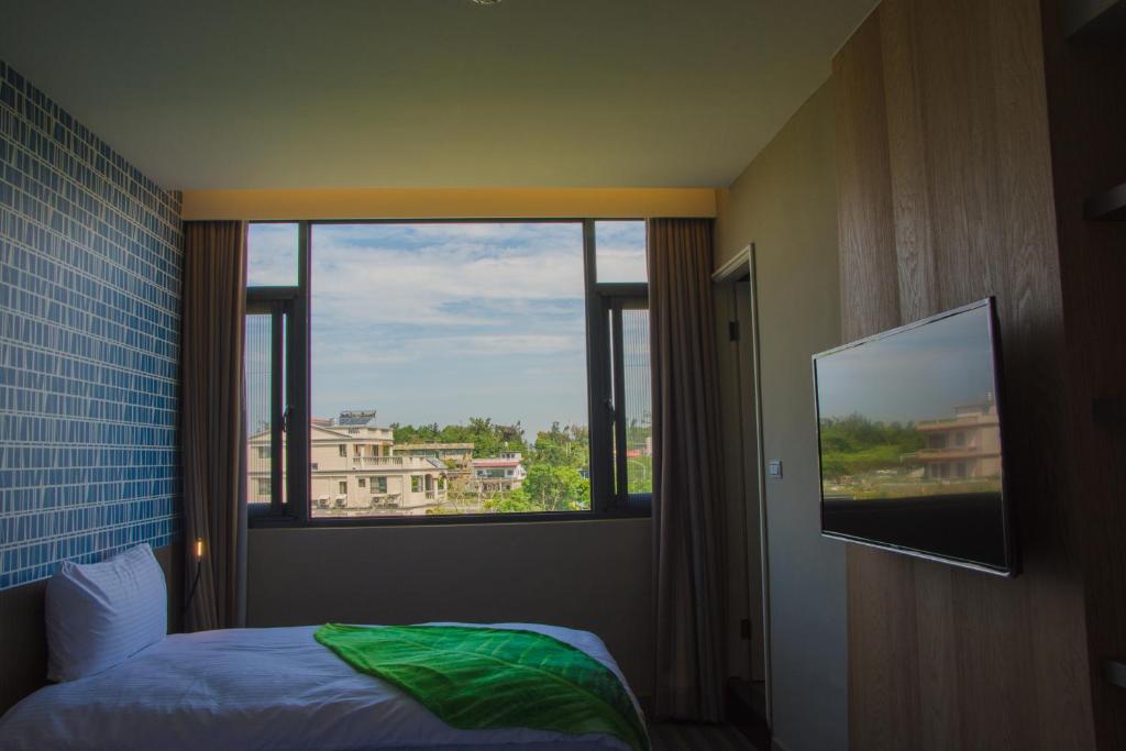 金宁乡三元民宿 的一间卧室设有窗户、一张床和一台电视。
